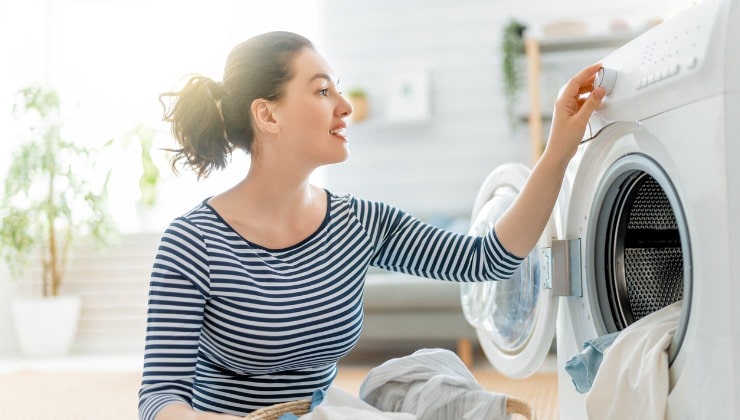 Une femme charge du linge dans une machine à laver
