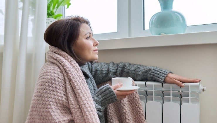 Une femme se réchauffe près du radiateur