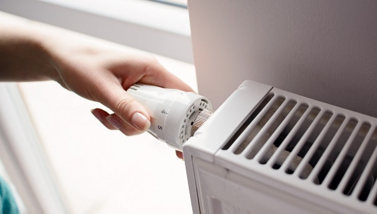 La mano baja el termostato del radiador