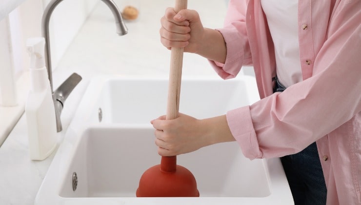 A woman uses the plunger of a sink