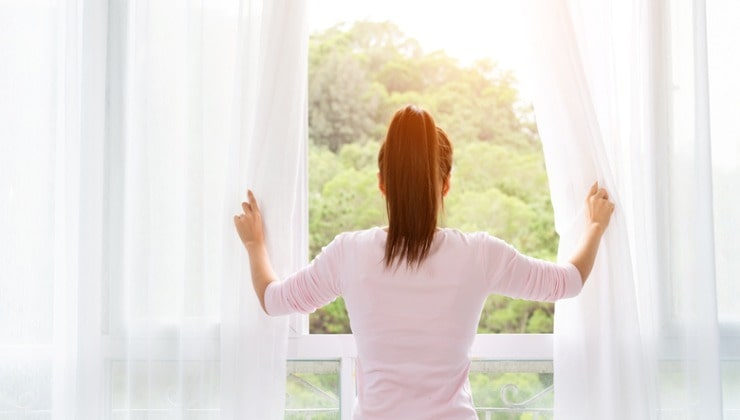 La femme ouvre les rideaux très blancs