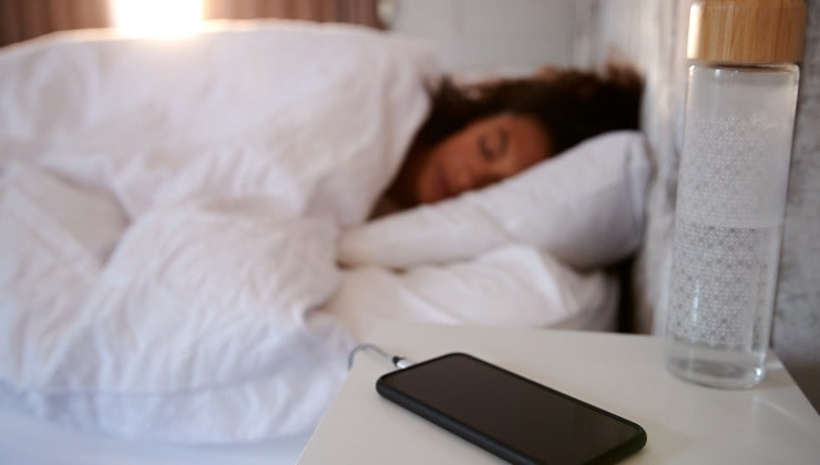 Mujer duerme con celular en la mesita de noche