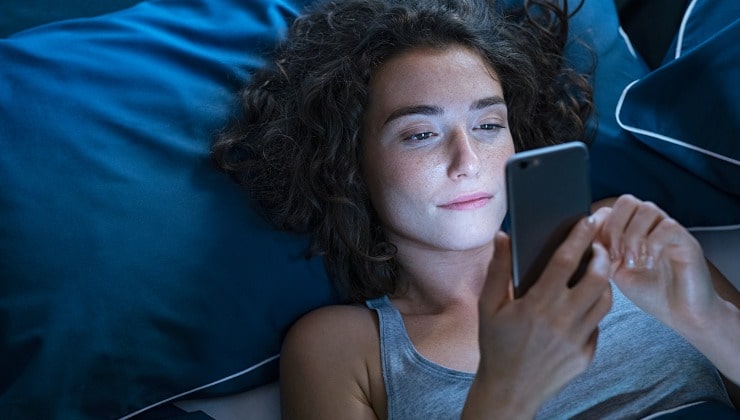 La fille utilise le téléphone portable la nuit dans le lit