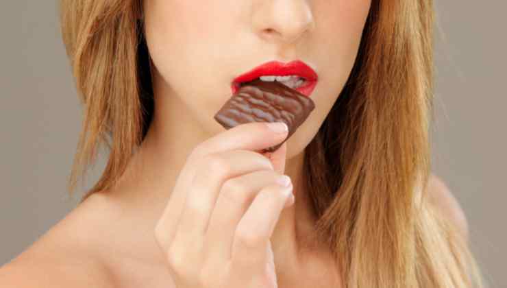 Donna che mangia tavoletta di cioccolato